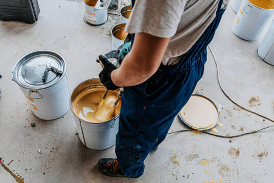 An epoxy flooring contractor mixing epoxy with a power tool.