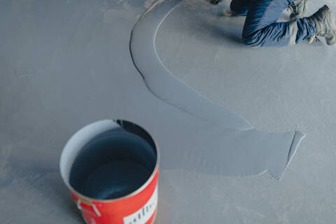 Gray epoxy being installed on a concrete floor.