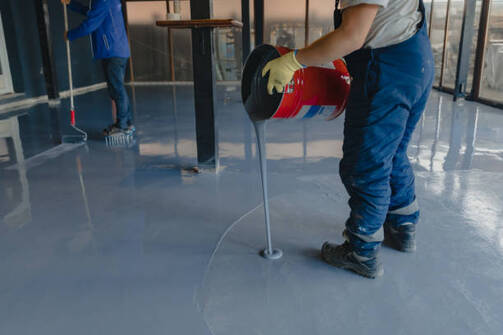 Person pouring epoxy from a bucket onto a floor in Norwalk.