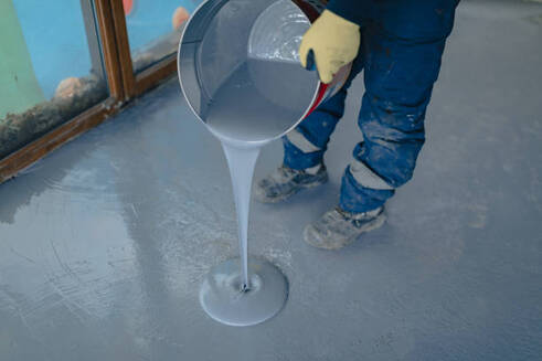 Person using a bucket to pour epoxy for installation in Norwalk.