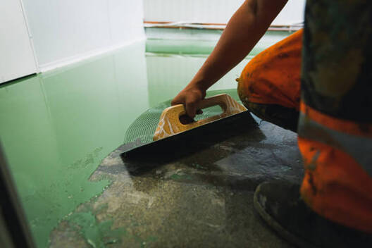 A man installing epoxy flooring on a concrete flooring in Norwalk.