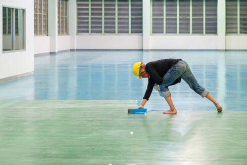 Person installing epoxy flooring with a trough at an industrial location in Norwalk.