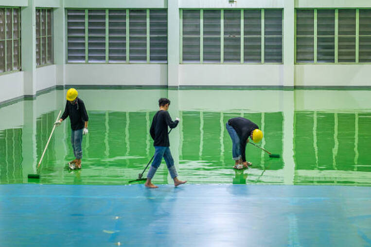 Team of epoxy floor installers rolling epoxy at an industrial location in Norwalk.