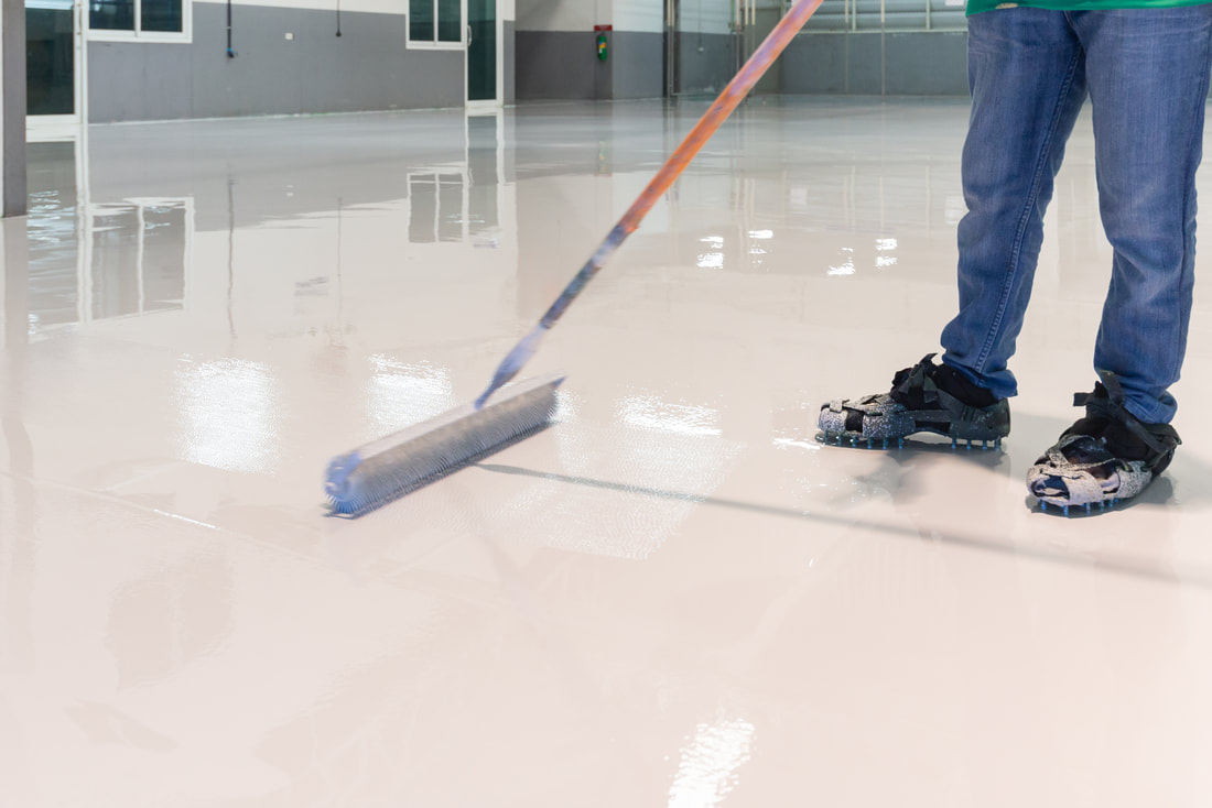 Person using a roller to install epoxy flooring in a commercial building in Norwalk, CT.