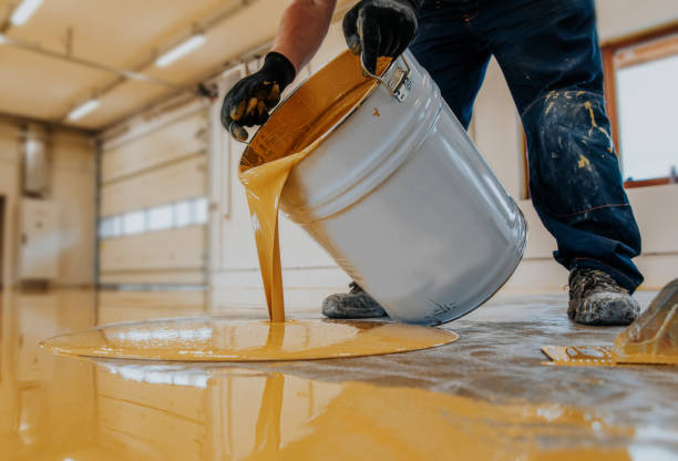 Man pooring yellow epoxy flooring from a bucket in Norwalk, CT.