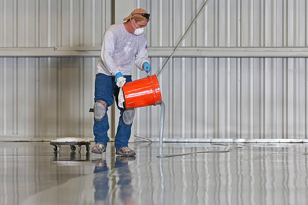 Man pouring epoxy from a bucket for installation.  