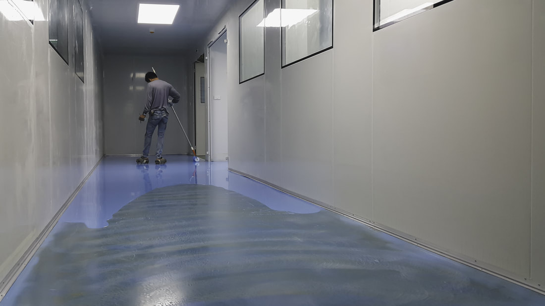 Person rolling epoxy flooring in a hallway of a commercial building in Norwalk.